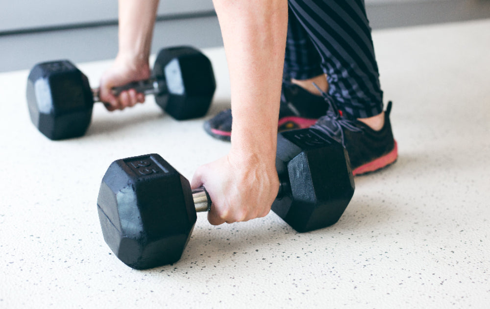 Person exercising with dumbbells on a speckled surface